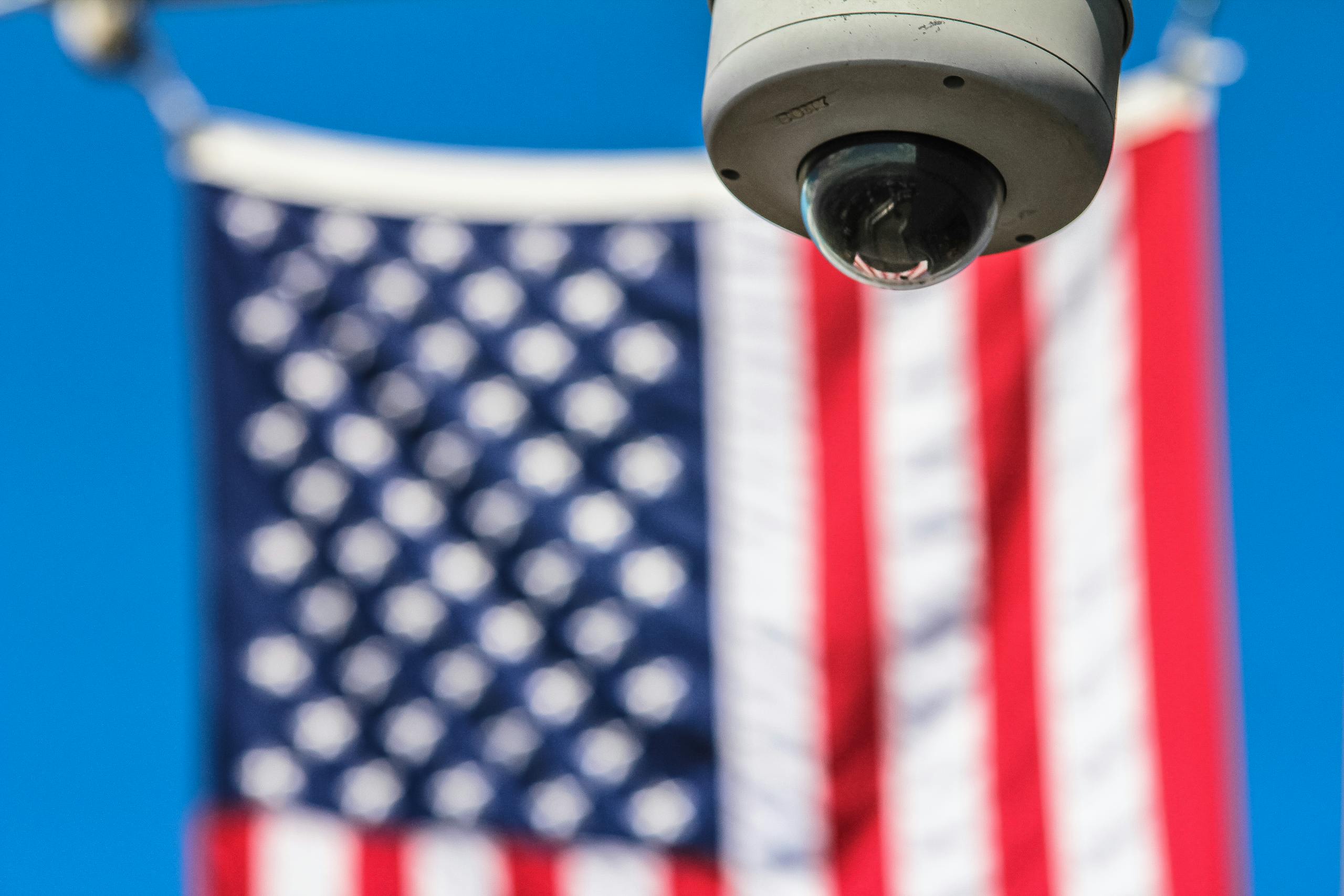 White dome camera in front of an American flag.